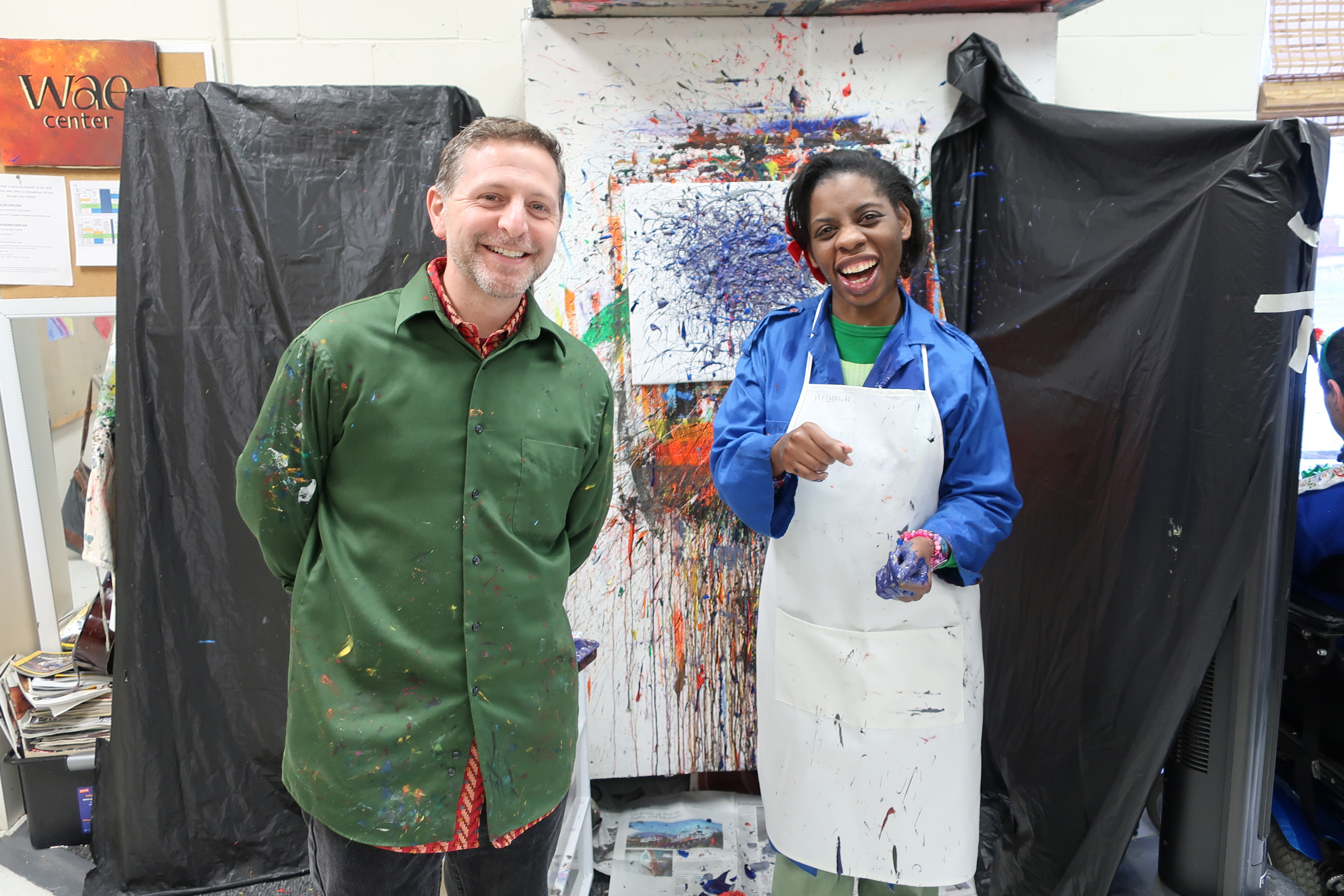 Mishawn and Adam Swart pose in front of her splatter painting.